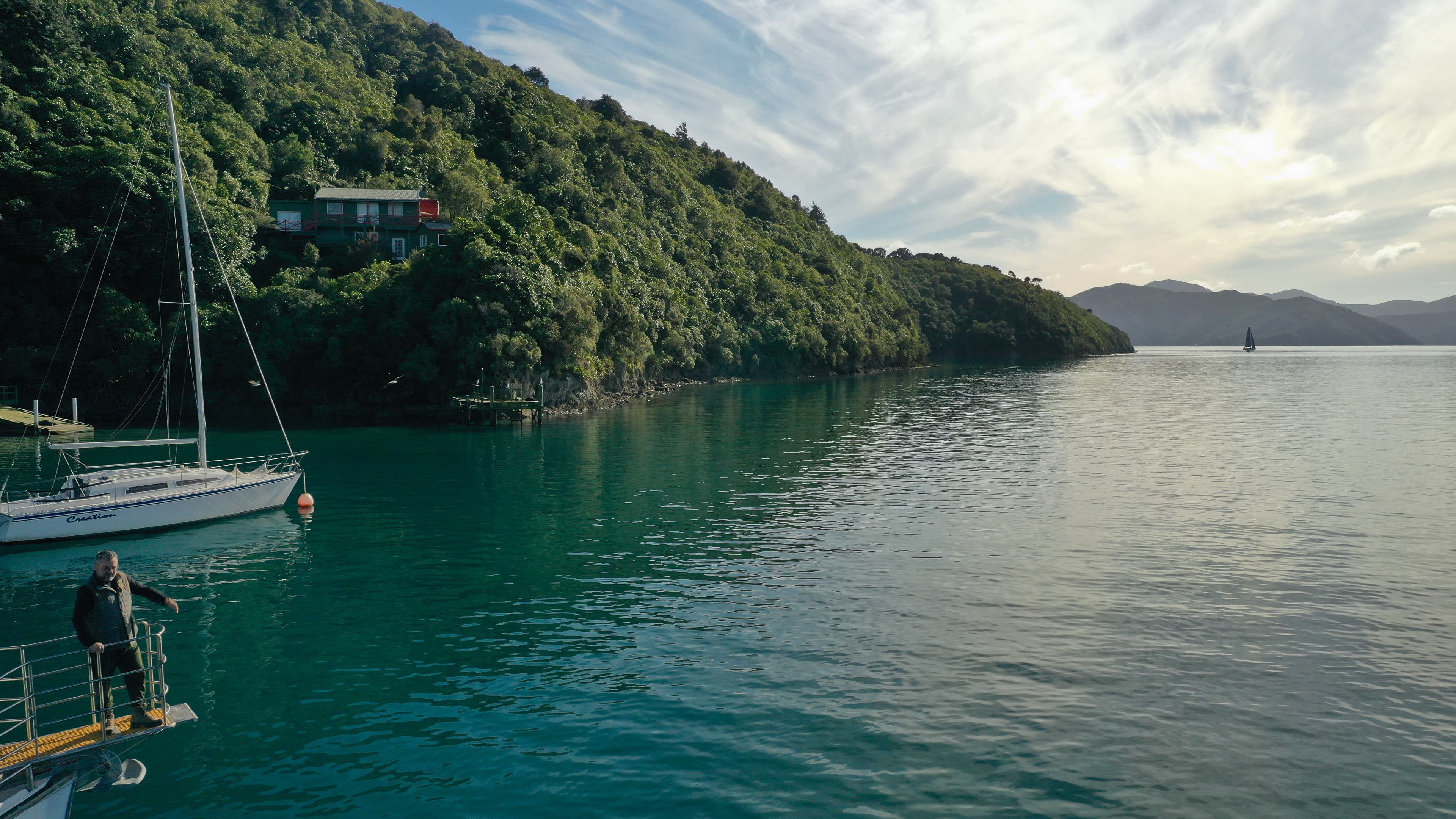 A yacht moored in a sheltered, bush-clad bay