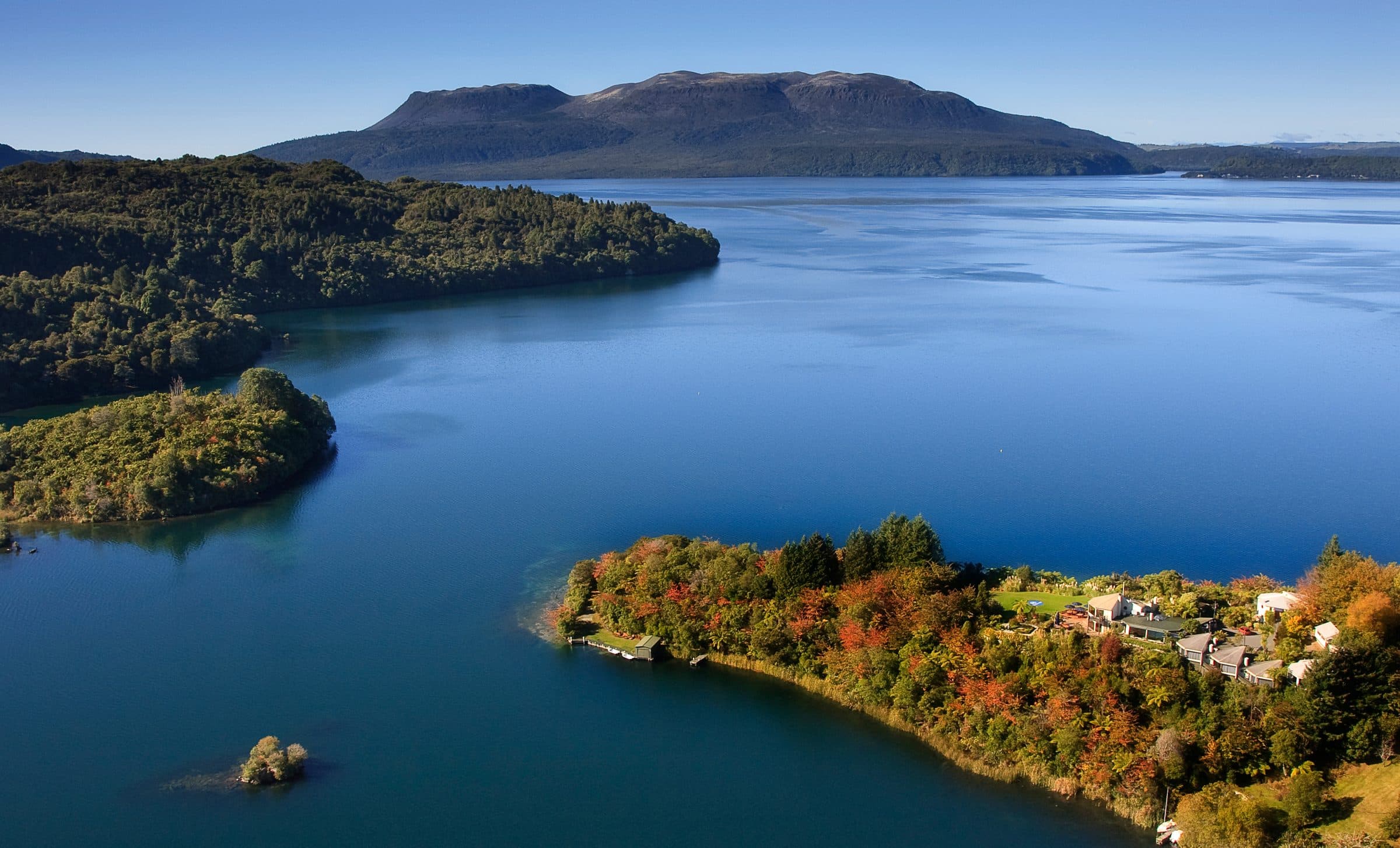 Solitaire Lodge on its private peninsula reaching into Lake Tarawera, Mount Tarawera beyond
