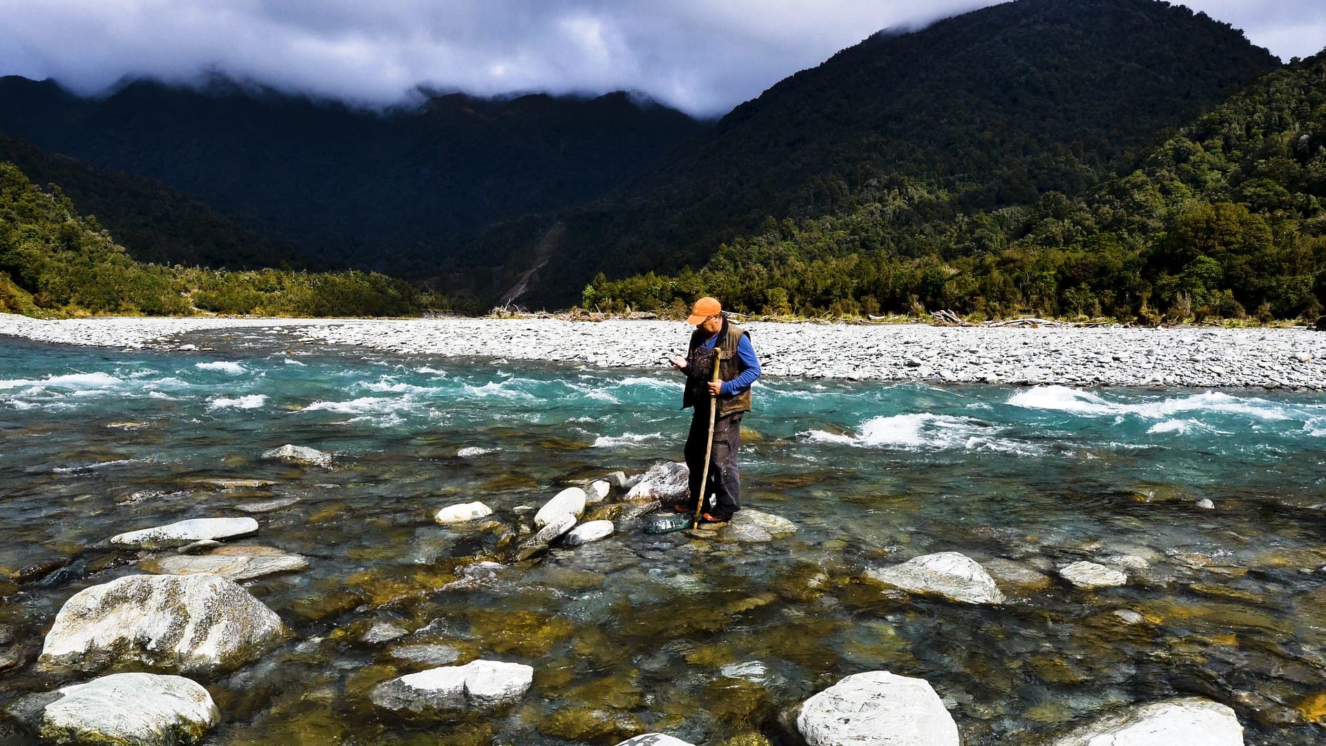 Bevan Climo standing in a West Coast river, searching for pounamu