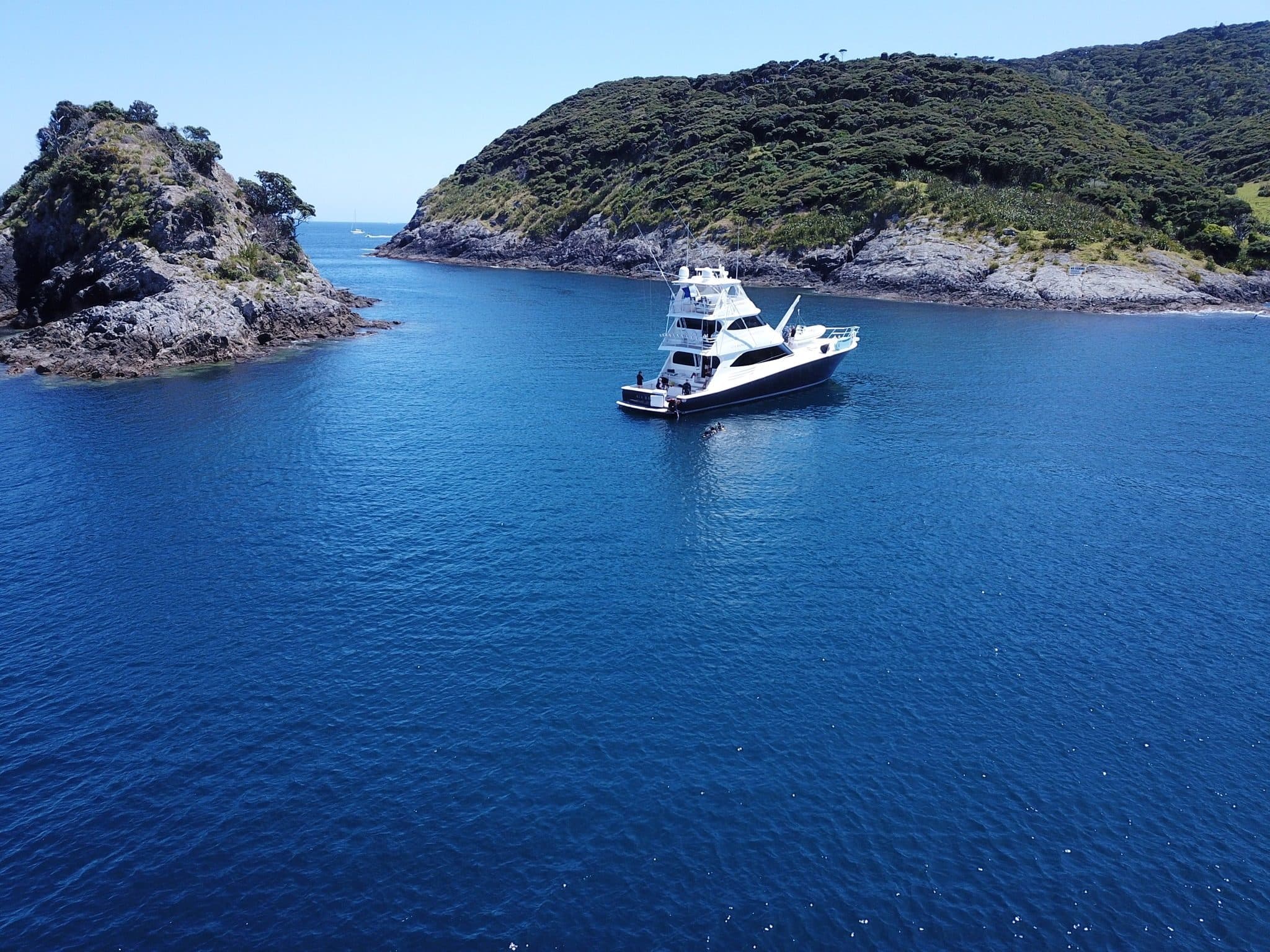 A private vessel at anchor in the clear blue water of the Bay of Islands at The Landing